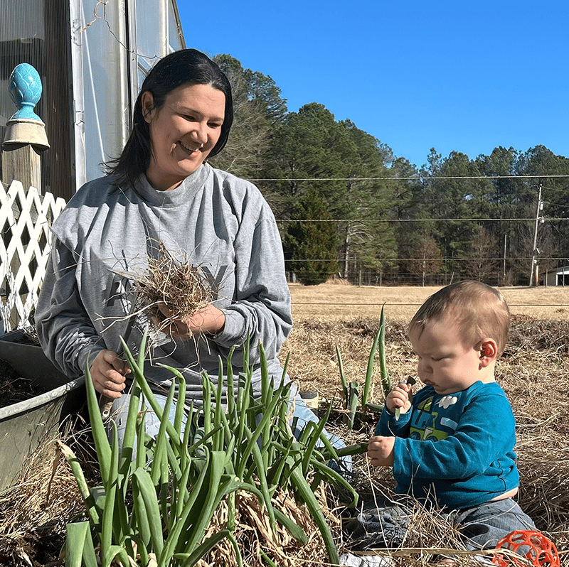 Millport Alabama Farmers Market founder and kid plant seeds in their local garden